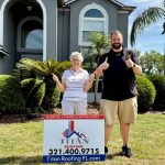 Man and woman posing by Titan Roofing sign