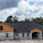 Roof installation underway on a partially built house