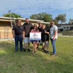 Several people presenting Titan Roofing signage