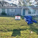 Titan Roofing sign behind home with roof replacement in progress
