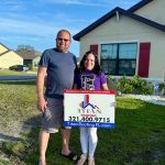 Two individuals displaying a Titan Roofing sign