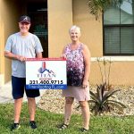 Two people holding a Titan Roofing sign