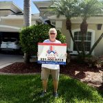 White-haired man holding Titan Roofing sign